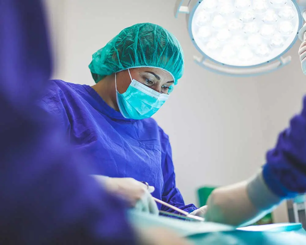Chirurgin mit Haube und Mundschutz im Operationssaal